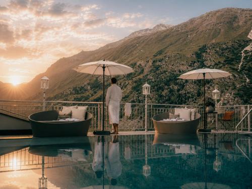 a man standing next to a pool at a resort at Gourmet & Wine Hotel Austria - 4 Sterne superior - Hike & Bike in Obergurgl