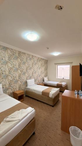 a hotel room with three beds and a window at براديس لاند نبراس الهدئ in Mecca