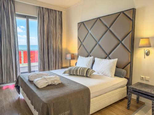 a bedroom with a large bed and a balcony at Olympus Thea Boutique Hotel in Platamonas