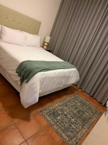 a bedroom with a bed with a green blanket on it at Essie's Place in Windhoek