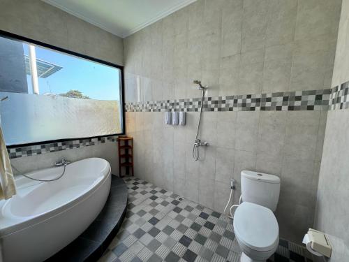 a bathroom with a tub and a toilet and a sink at Ramantika Sunset Bay in Nusa Dua