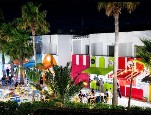 a building with people sitting at tables in front of it at The Village Resort By Acquaviva Gammarth in Gammarth
