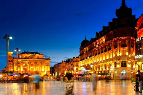 un grupo de personas caminando delante de los edificios por la noche en Duplex 120m2 Central Comédie Corum Climatisation Parking, en Montpellier