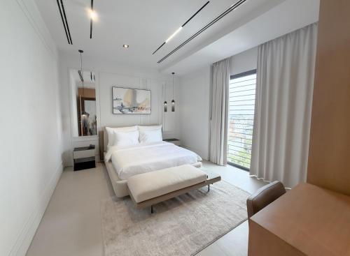 a white bedroom with a bed and a table at Barobi Apartment in Solpur