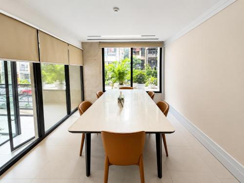 a dining room with a table and chairs and windows at Barobi Apartment in Solpur