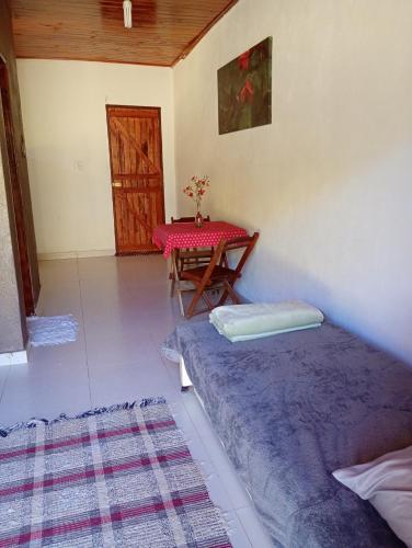 a living room with a table and a bed at Chalé Caminho Real in Itamonte