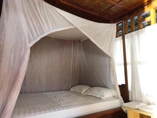 a bed in a room with a mosquito net at Losmen Togean Wisata in Pulau Togian