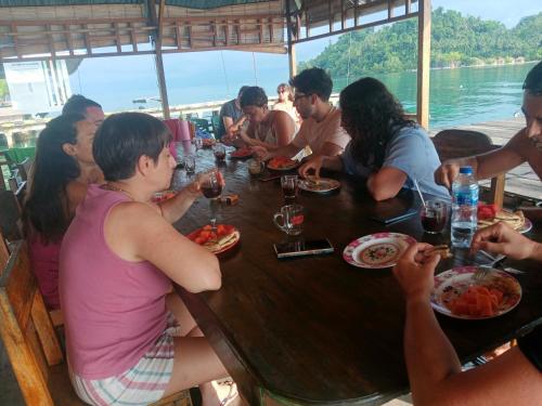 a group of people sitting around a table eating food at Losmen Togean Wisata in Pulau Togian