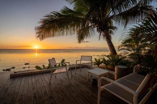 a deck with chairs and a sunset on the beach at Villa Marea - Exceptional Beachfront Sanctuary in Tamarin