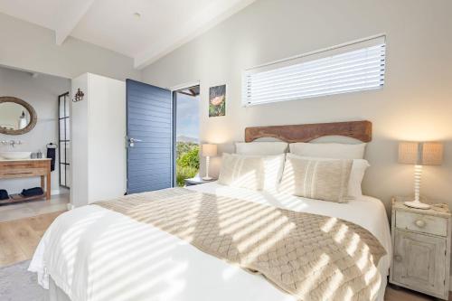a bedroom with a large white bed and a window at Chapmans Corner Studio in Noordhoek