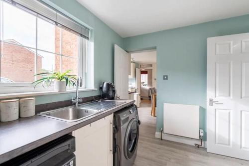 a kitchen with a sink and a washing machine at Bright Double Room with Shared Bathroom in Luton