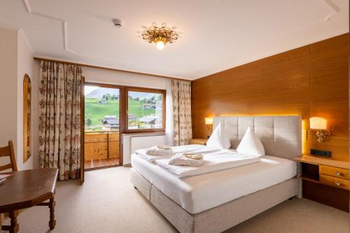 a bedroom with a bed and a desk and a window at Hotel Elisabeth in Schoppernau