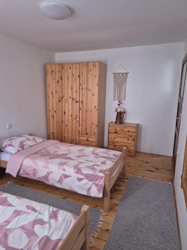 a bedroom with two beds and a wooden wall at Apartmani Andrej in Udbina