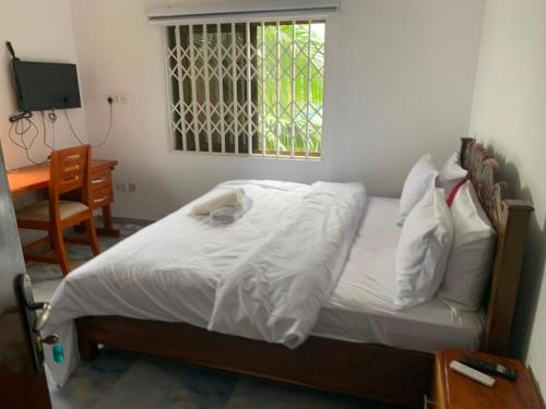 a bedroom with a bed with white sheets and a window at Tranquility Lodge in Abrekuma