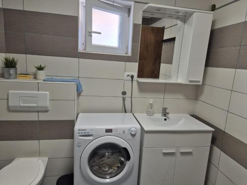 a bathroom with a washing machine and a sink at Apartmani Andrej in Udbina