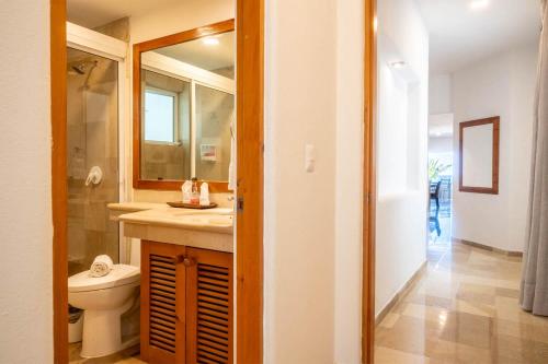 a bathroom with a toilet and a sink and a mirror at Costa Brava Apartments I Ocean Front in Puerto Aventuras