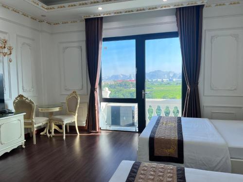 a bedroom with two beds and a table and a large window at The Téa Opera Hotel - Hoa Đông Aureum in Châu Cầu