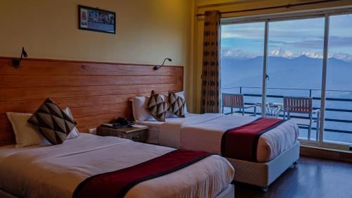 a hotel room with two beds and a balcony at Hotel Green Valley Nagarkot in Nagarkot