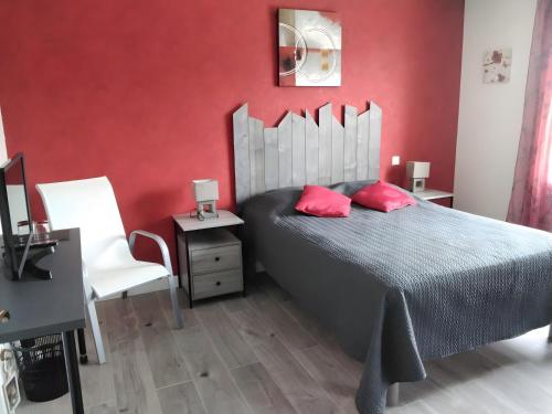a bedroom with red walls and a bed with two red pillows at Chambres d'hôtes Les Écureuils in Saint-Laurent-de-la-Prée
