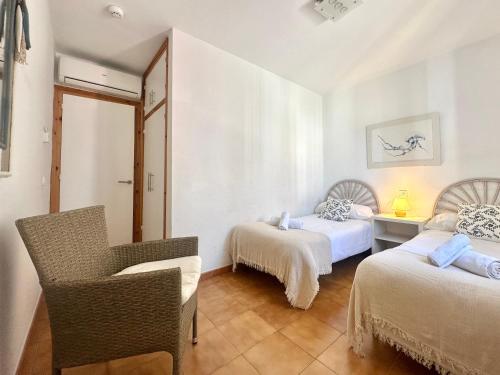 a room with two beds and a chair in it at White Sands 4.20 in Arenal d'en Castell