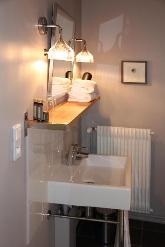 a bathroom with a sink and a shelf with towels at Hôtel Courtille de Solutré in Solutré-Pouilly