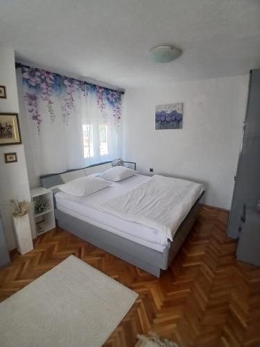 a bedroom with a white bed and wooden floors at Luce in Tomislavgrad