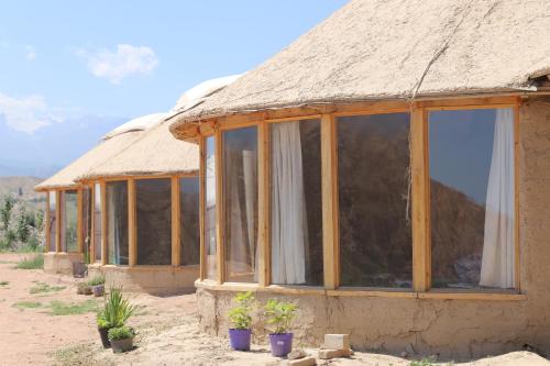 a thatch roofed house with potted plants in front of it at Asman Tör Yurt Camp in Tong