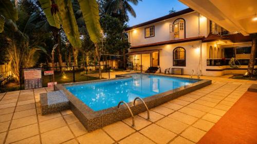 a swimming pool in front of a house at Colors Fly Hotel in Colva