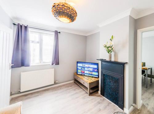 a living room with a fireplace and a tv at 4 Bed - 2 Baths 1 Walk in Shower Lots of Parking in Ipswich