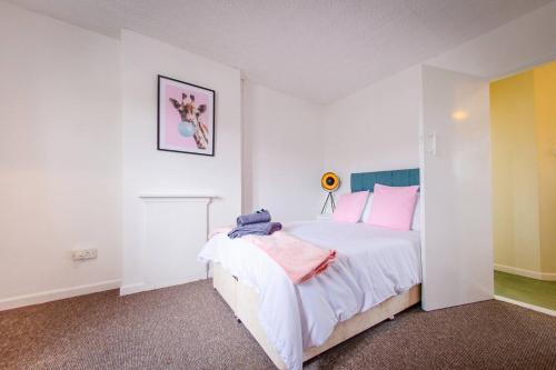 a white bedroom with a bed with pink pillows at 4 Bed - 2 Baths 1 Walk in Shower Lots of Parking in Ipswich
