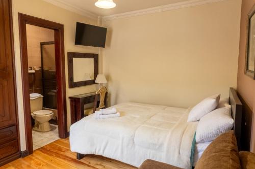 a bedroom with a white bed and a couch at La POSADA CUENCANA EN CUENCA in Cuenca