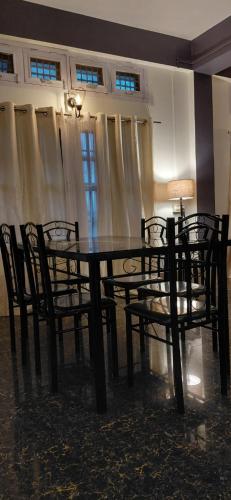 a dining room with a table and chairs and a lamp at Pipits cozynest in Tezpur
