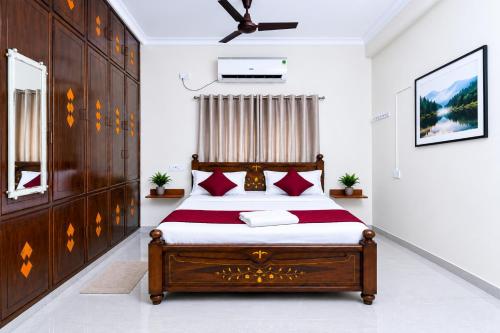 a bedroom with a wooden bed with red pillows at SLS Homestay - Luxury AC Service Apartments 1BHK, 2BHK, 3BHK - Direct Flyover to Alipiri Tirumala Gate - Walk to PS4 Pure Veg Restaurants, Supermarkets - Near to National Highway & Padmavathi Amma Temple - Modular Kitchen, Living room -Free Superfast Wifi in Tirupati