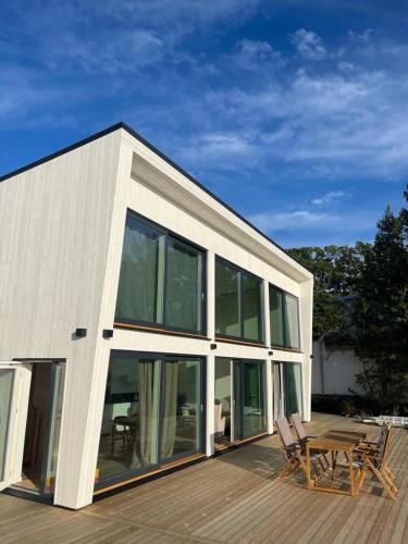 a house with glass windows and a wooden deck at Seaside panorama Villa with JETLESS hot tub in Gothenburg