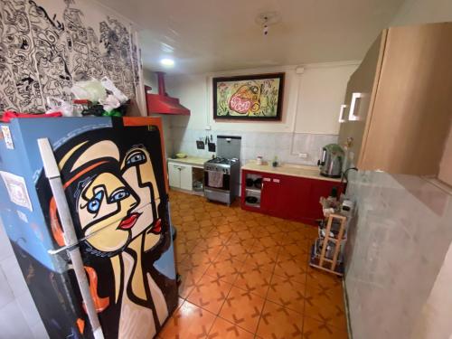 a kitchen with a refrigerator with a painting on it at La Mancha Art Hostel - Cerro Alegre - Valparaiso in Valparaíso