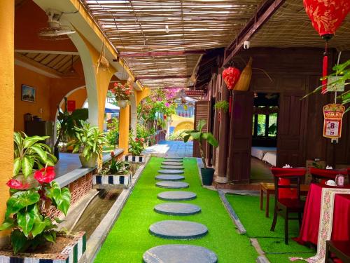 a patio with green grass and a pathway with plants at Twin Double Room in Phú Ngọc (1)