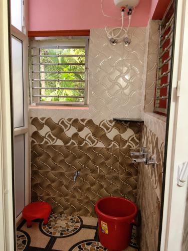 a bathroom with a red toilet and a window at Omkar Homestay - Honavar in Kāsarkod