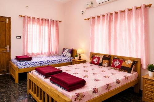 a bedroom with two beds and two windows at Omkar Homestay - Honavar in Kāsarkod