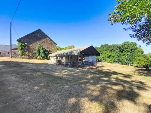 a large building with a tent in a field at Lodge La Belle Vie in Vigeois