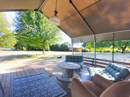 a patio with a table and couches and an umbrella at Lodge La Belle Vie in Vigeois