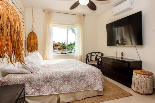 a bedroom with a bed and a tv and a window at Stunning Large Remodeled Penthouse-Big Canal Views in Puerto Aventuras