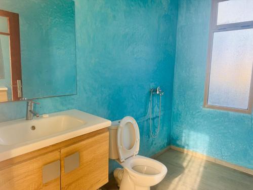 a blue bathroom with a toilet and a sink at Sisi villa in Essaouira