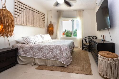 a bedroom with a bed and a tv and a window at Stunning Large Remodeled Penthouse-Big Canal Views in Puerto Aventuras