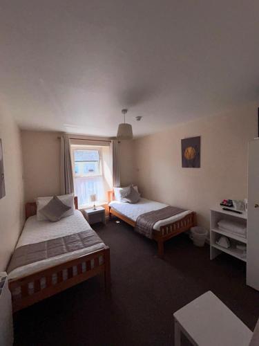 a bedroom with two beds and a window at O'Loughlin's Bar in Milltown Malbay