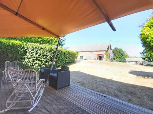 a deck with chairs and an umbrella and a house at Lodge La Vie Douce in Vigeois