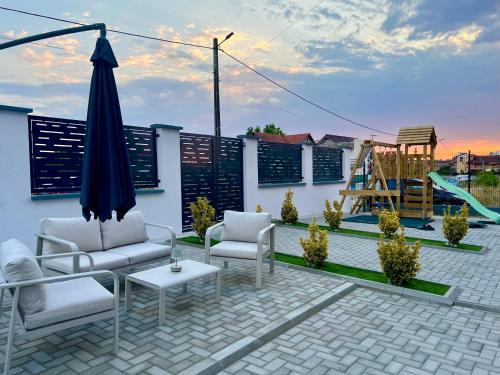 a patio with chairs and an umbrella and a playground at Vila Marbo in Baile Felix