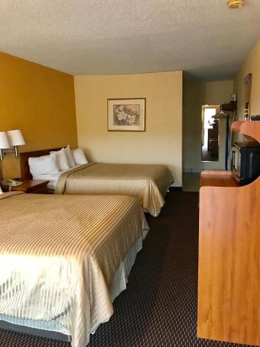 a hotel room with two beds and a television at Coachman's Inn in Magnolia