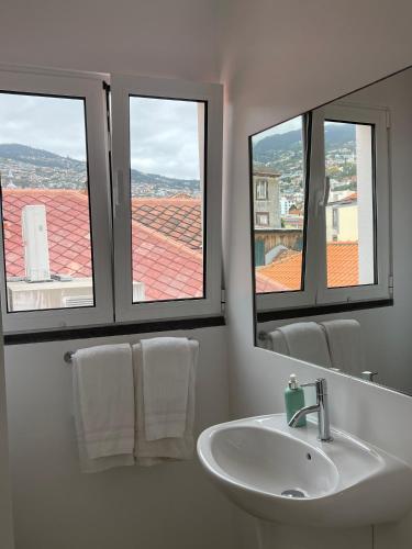 a bathroom with a sink and two windows at Esmeralda Holidays Apartments in Funchal