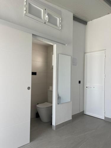 a white bathroom with a toilet and a mirror at Habitación Manzanilla in Sanlúcar de Barrameda