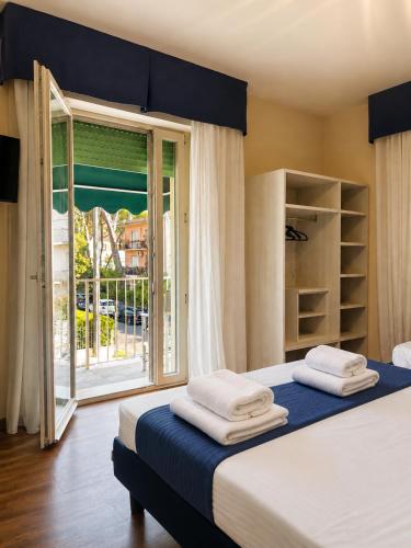 a bedroom with a bed with towels on top of it at Hotel Liu in Lido di Camaiore